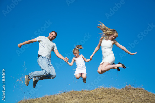 young family dad mom daughter jumping on haystack