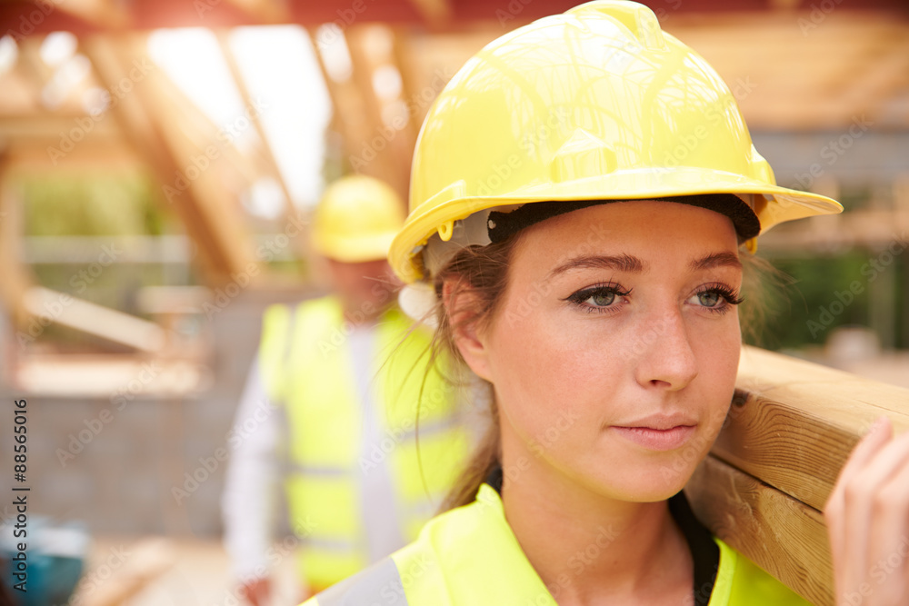 Builder And Female Apprentice Carrying Wood On Site Builder And Female Apprentice Carrying Wood On Site