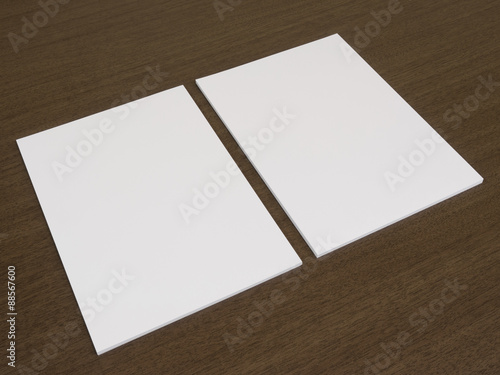 Two blank white documents on a wooden background.