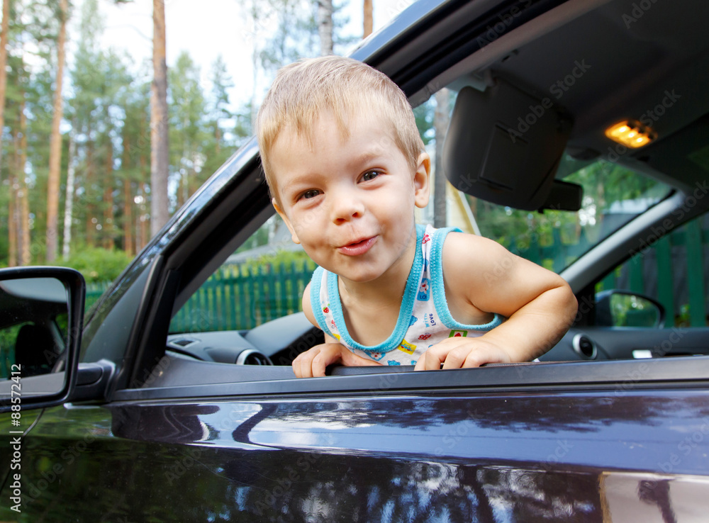 Funny small kid looking from open car window Funny small kid looking from open car window