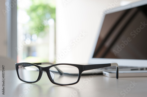 close up glasses on work desk with laptop