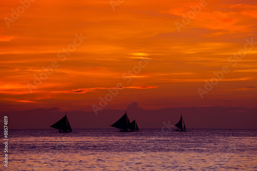 Sunset on beach with sailing boats