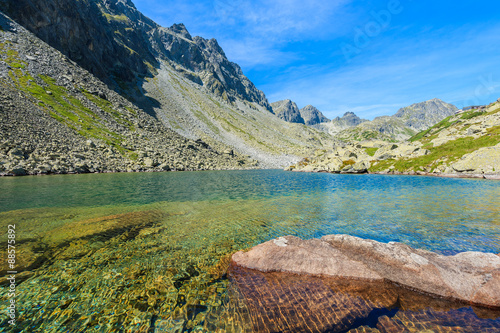 Stones in crystal clear water of alpine lake in summer landscape of Starolesna valley, High Tatra Mountains, Slovakia
