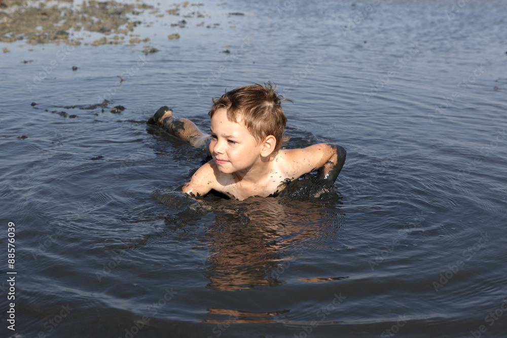 Kid lying in the black mud