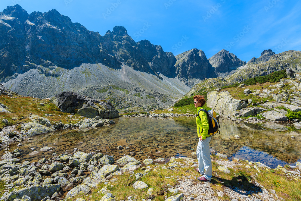 Young woman tourist knelled on edge of small lake in Starolesna valley, High Tatra Mountains, Slovakia