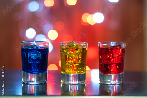 Three glasses with berry liqueur on the bar counter at a