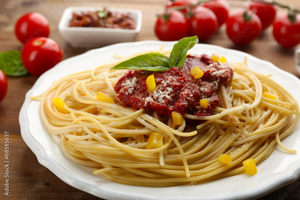 Spaghetti with tomato sauce, paprika and cheese on white plate, on color wooden background Spaghetti with tomato sauce, paprika and cheese on white plate, on color wooden background