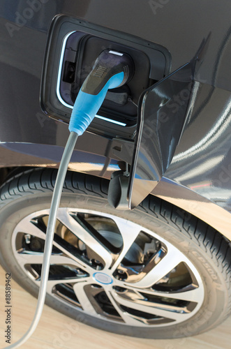 Modern electric car plugged in to power supply charging station