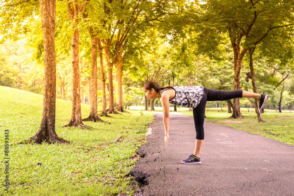 Fototapeta premium Side view of woman runner stretching warm up with single-leg dea