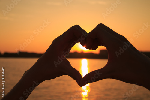 Heart-shaped hand against the sunset