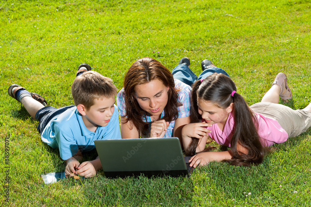 Happy Family using laptop lying on grass Happy Family using laptop lying on grass