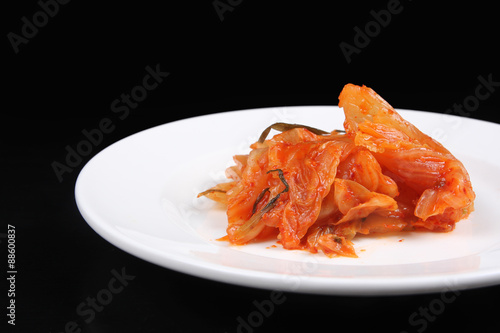 Kimchi on white plate against black background