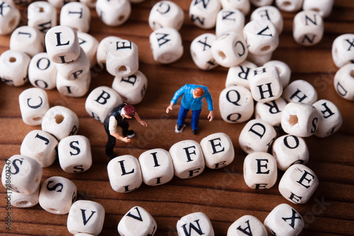アルファベットのブロックと仕事をしているミニチュア人形