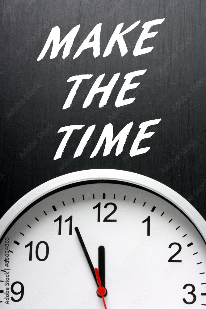 The phrase Make The Time in white text on a blackboard above a modern wall clock with the hands pointing at twelve midnight The phrase Make The Time in white text on a blackboard above a modern wall clock with the hands pointing at twelve midnight