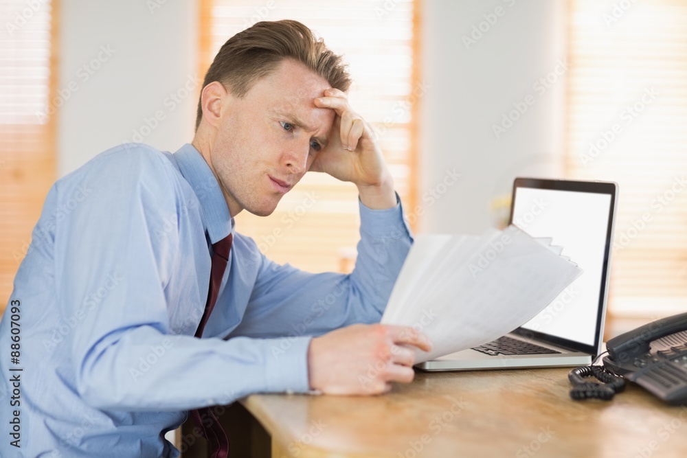 Focused businessman reading document at desk Focused businessman reading document at desk