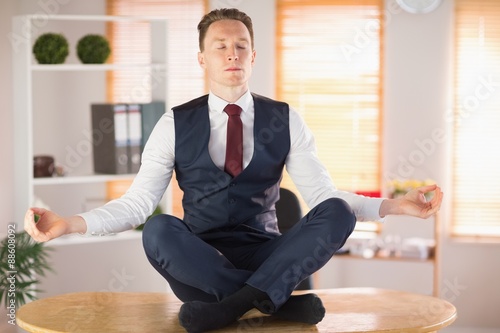 Calm businessman meditating in lotus pose