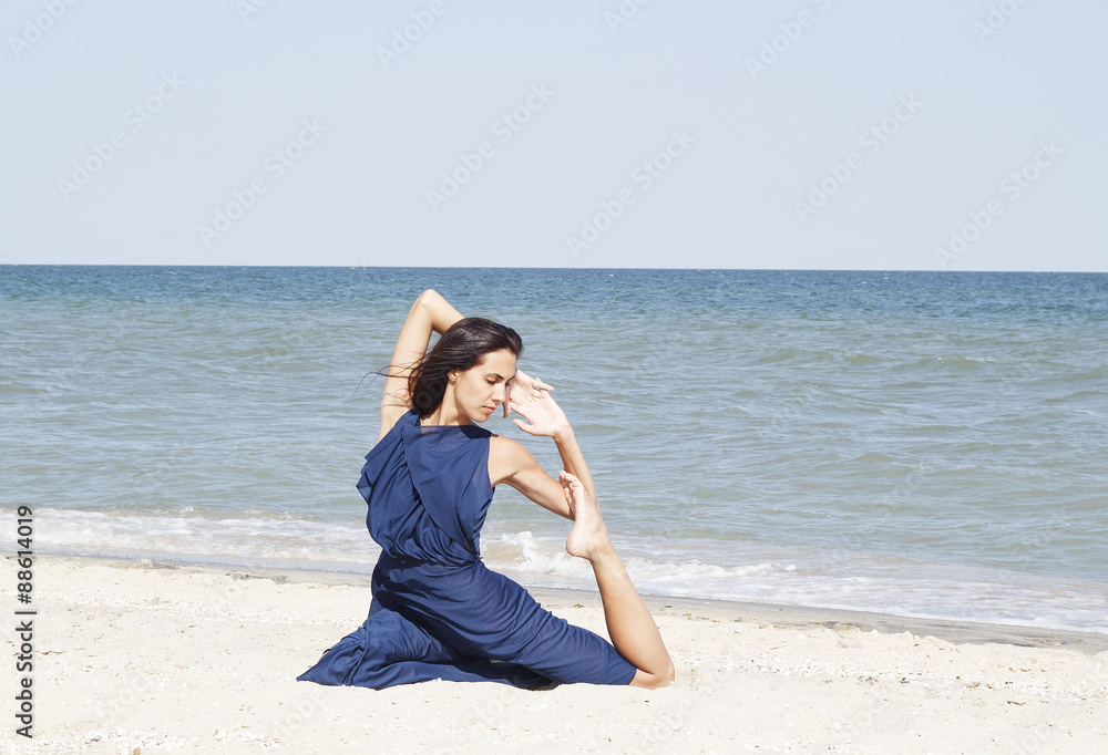 Young beautiful woman doing yoga at seaside in blue dress Young beautiful woman doing yoga at seaside in blue dress