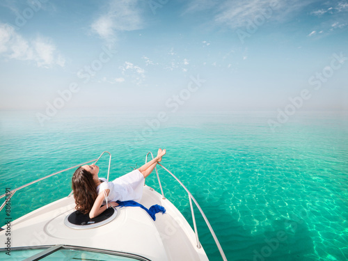 Young sexy woman lies in white dress enjoying on yacht at the sea photo