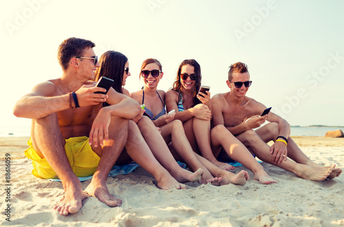 friends with smartphones on beach © Syda Productions