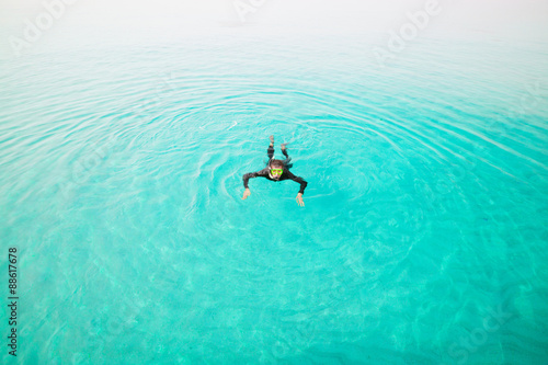 Man in diving suit swims in sea, top view. Activities on water. Diver
