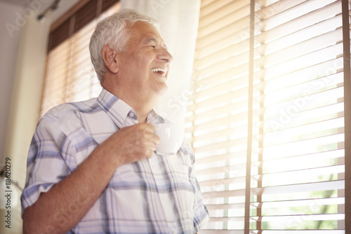 Elder man drinking coffee and looking through the window