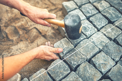 Fotografie Close-up of construction worker installing and laying pavement stones on terrace, road or sidewalk