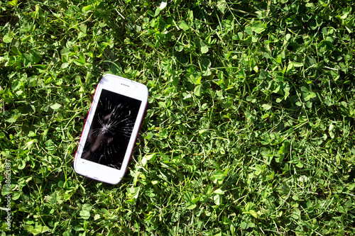 Smartphone with broken screen lying on the grass