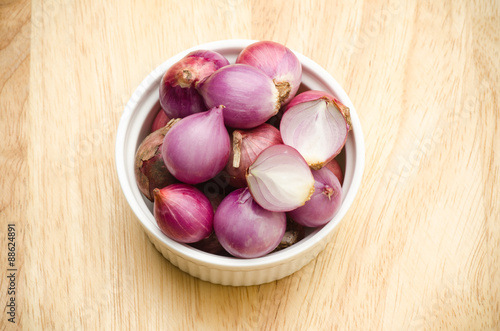 Close up of fresh shallots in the bowl on wooden background