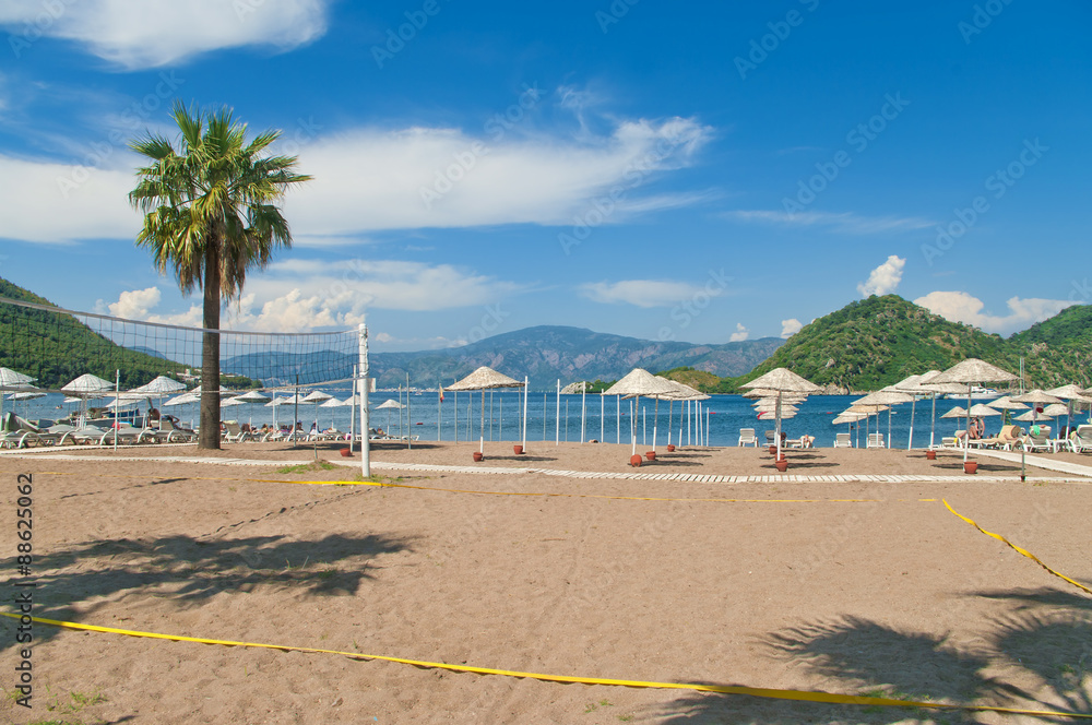 beach volleyball court with sunshades and sunbeds at background