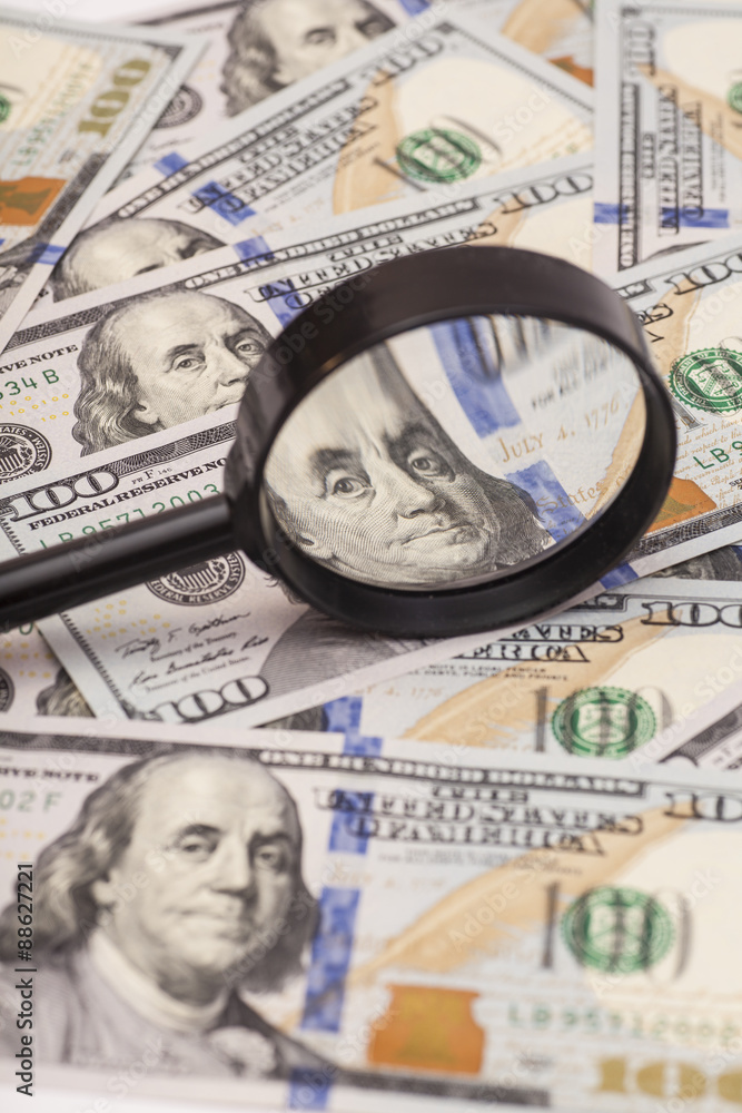 Hundred dollar banknotes under magnifying glass Hundred dollar banknotes under magnifying glass