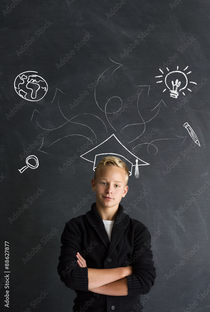 Intelligenter Jungen mit Doktorhut vor Tafel Intelligenter Jungen mit Doktorhut vor Tafel