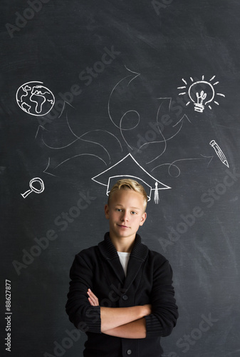 Obraz na plátně Intelligenter Jungen mit Doktorhut vor Tafel