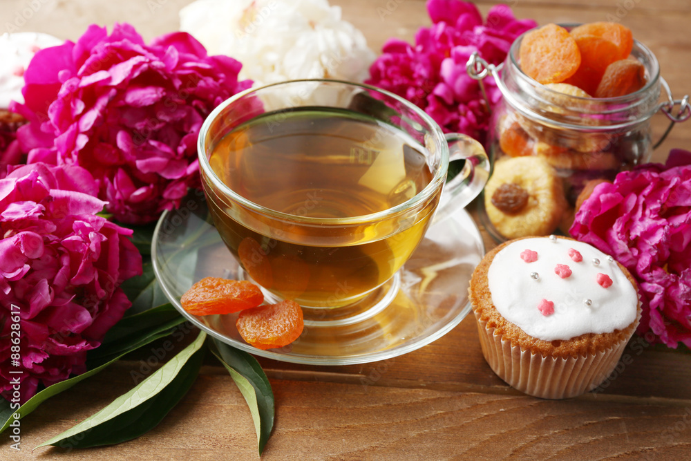 Composition with cup of herbal tea and peony flowers on wooden background Composition with cup of herbal tea and peony flowers on wooden background