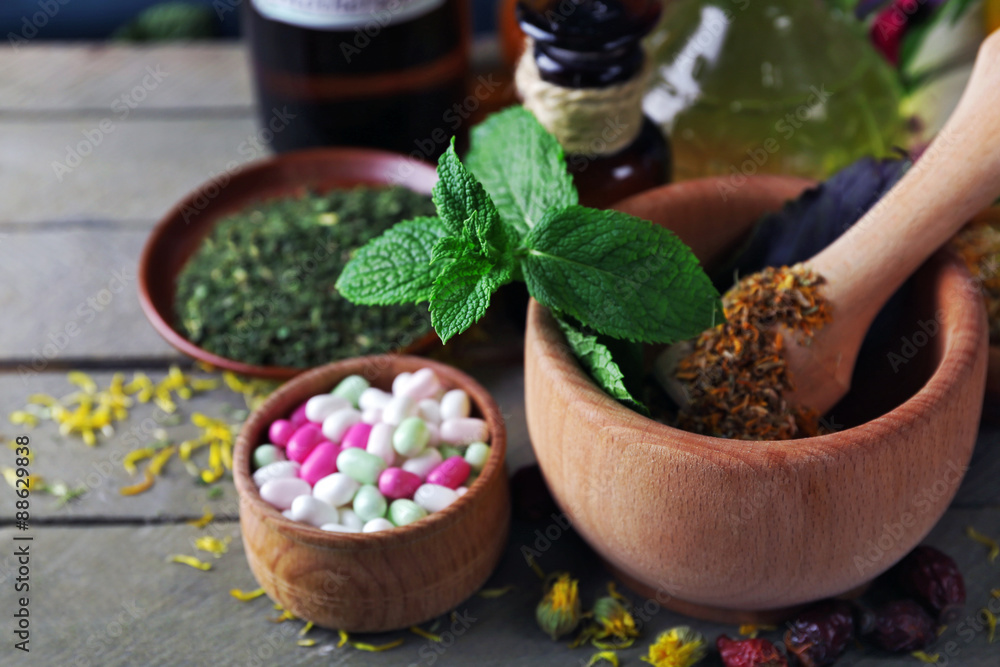 Herbs, berries, flowers and pills on color wooden table background Herbs, berries, flowers and pills on color wooden table background