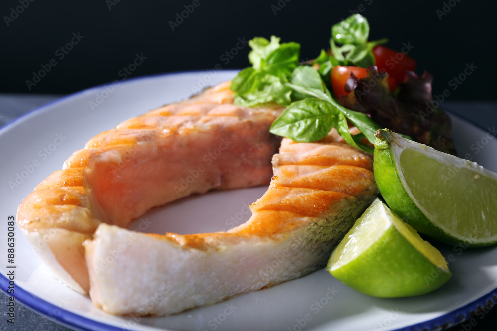 Tasty grilled salmon with lime and salad on table close up Tasty grilled salmon with lime and salad on table close up