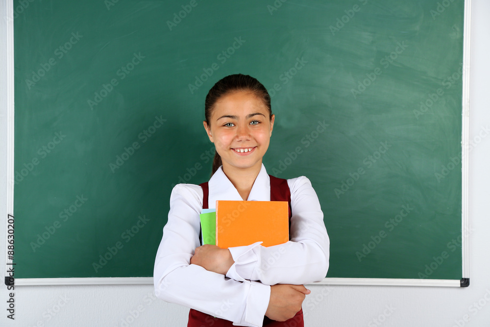 Beautiful little girl standing near blackboard in classroom Beautiful little girl standing near blackboard in classroom