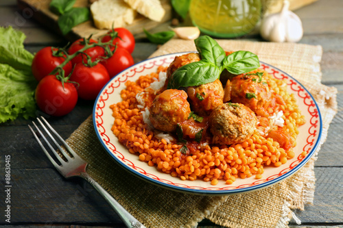 Meat balls with lentil and tomato sauce, wooden spoon on wooden background