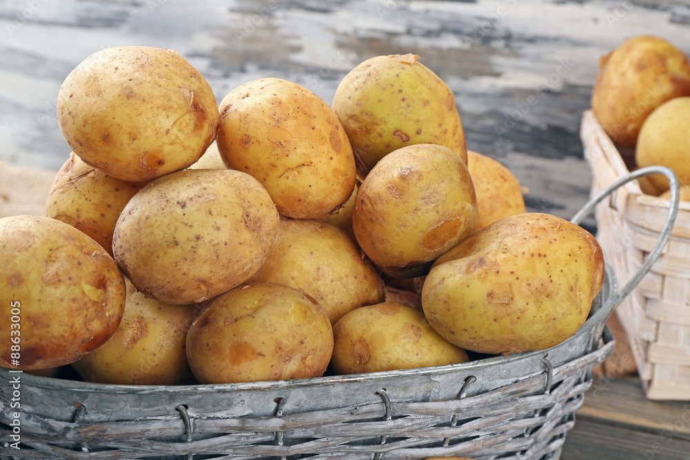 Young potatoes in wicker baskets on wooden table close up Young potatoes in wicker baskets on wooden table close up