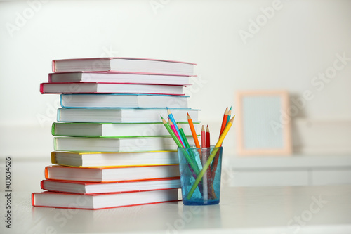 Colorful books and pencil on table in room photo