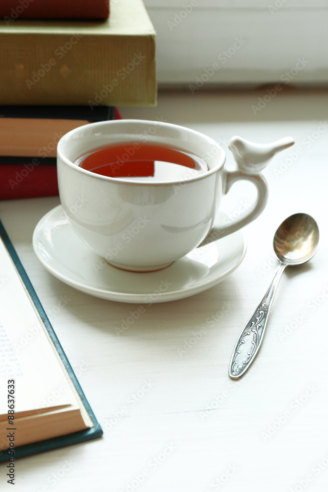 Cup of tea with stack of books on windowsill, closeup Cup of tea with stack of books on windowsill, closeup