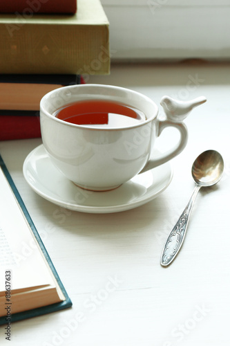 Cup of tea with stack of books on windowsill  closeup
