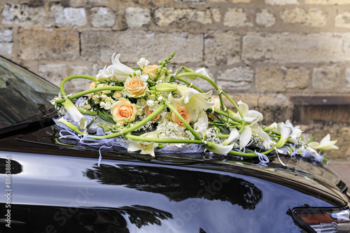 Wedding bouquet of white lilies and pink roses on the hood of the black car