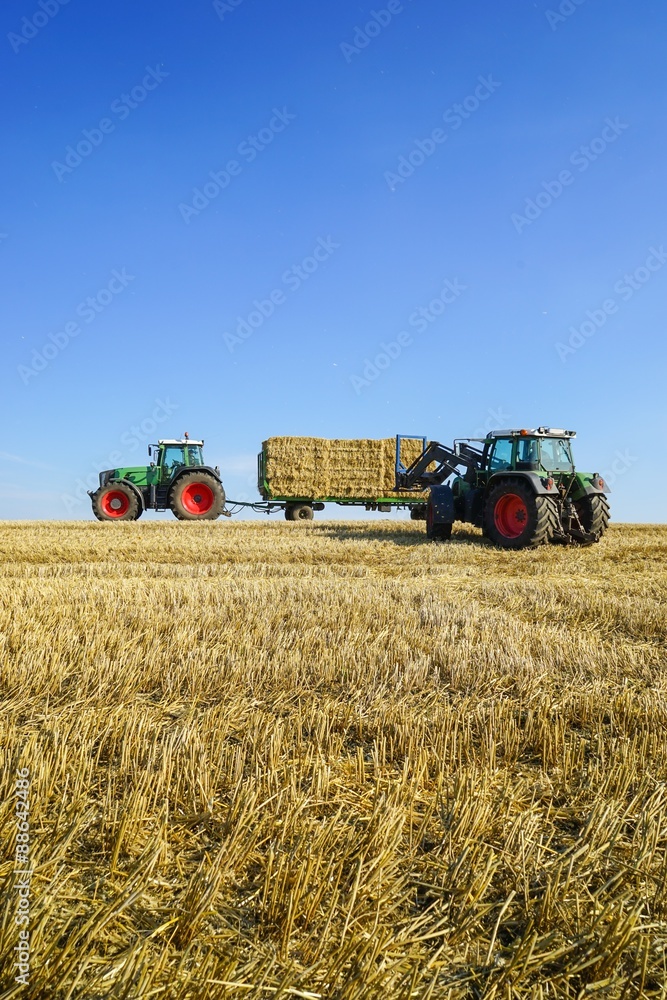 Traktor beim Verladen von Strohballen auf einen Anhänger Traktor beim Verladen von Strohballen auf einen Anhänger