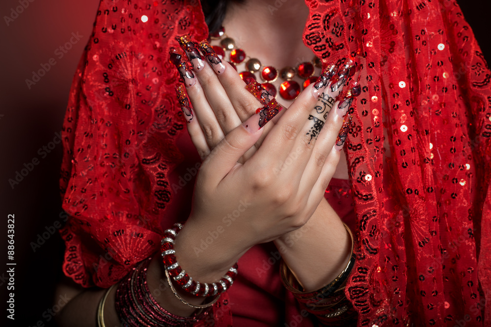 beautiful girl in the image of Indian woman in a red sari with beautiful patch acrylic nails in oriental style in the studio