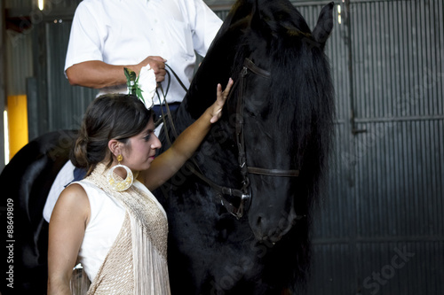 Bailaora de flamenco con caballo negro Árabe. Gitana flamenca y su caballo negro Árabe. Espectáculo de baile flamenco con caballos.