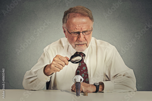 Fotografija businessman skeptically looking at small employee through magnifying glass