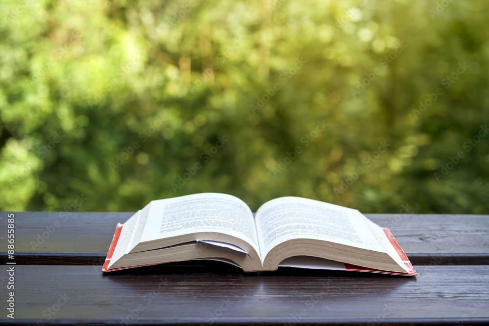 opened book on a garden wooden table opened book on a garden wooden table