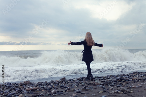 Woman in a black coat on the beach