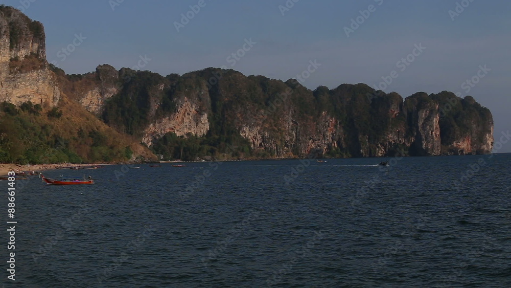 panorama of city beach with moored thai longtail boats and tourists against cliffs under acceleration panorama of city beach with moored thai longtail boats and tourists against cliffs under acceleration
