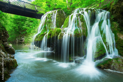 Cascade falls over mossy rocks in forest